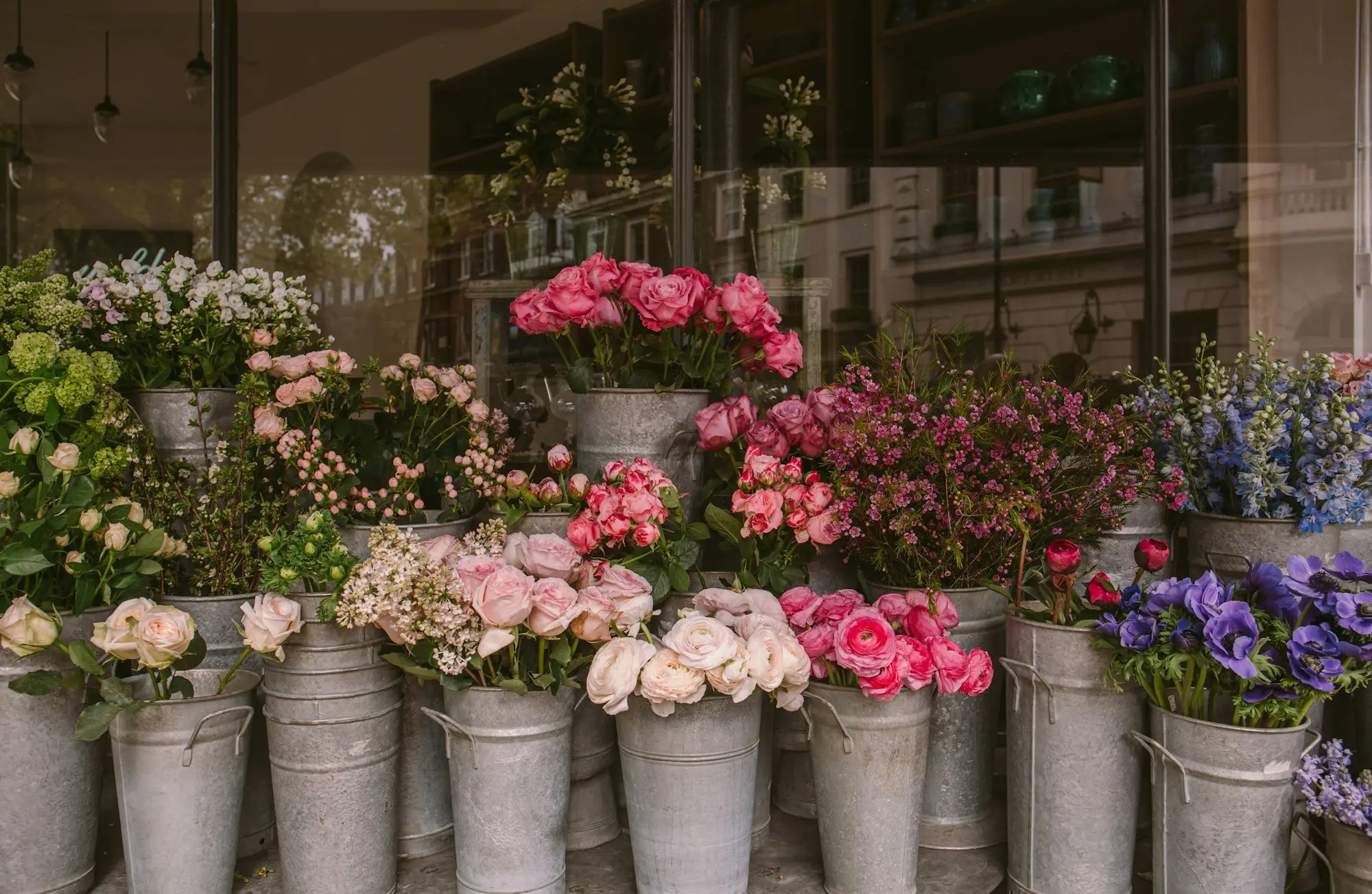 Florist shopfront with buckets of pink roses, peonies and hydrangeas lined up outside the window, the kind of small business weighing up a 100k loan