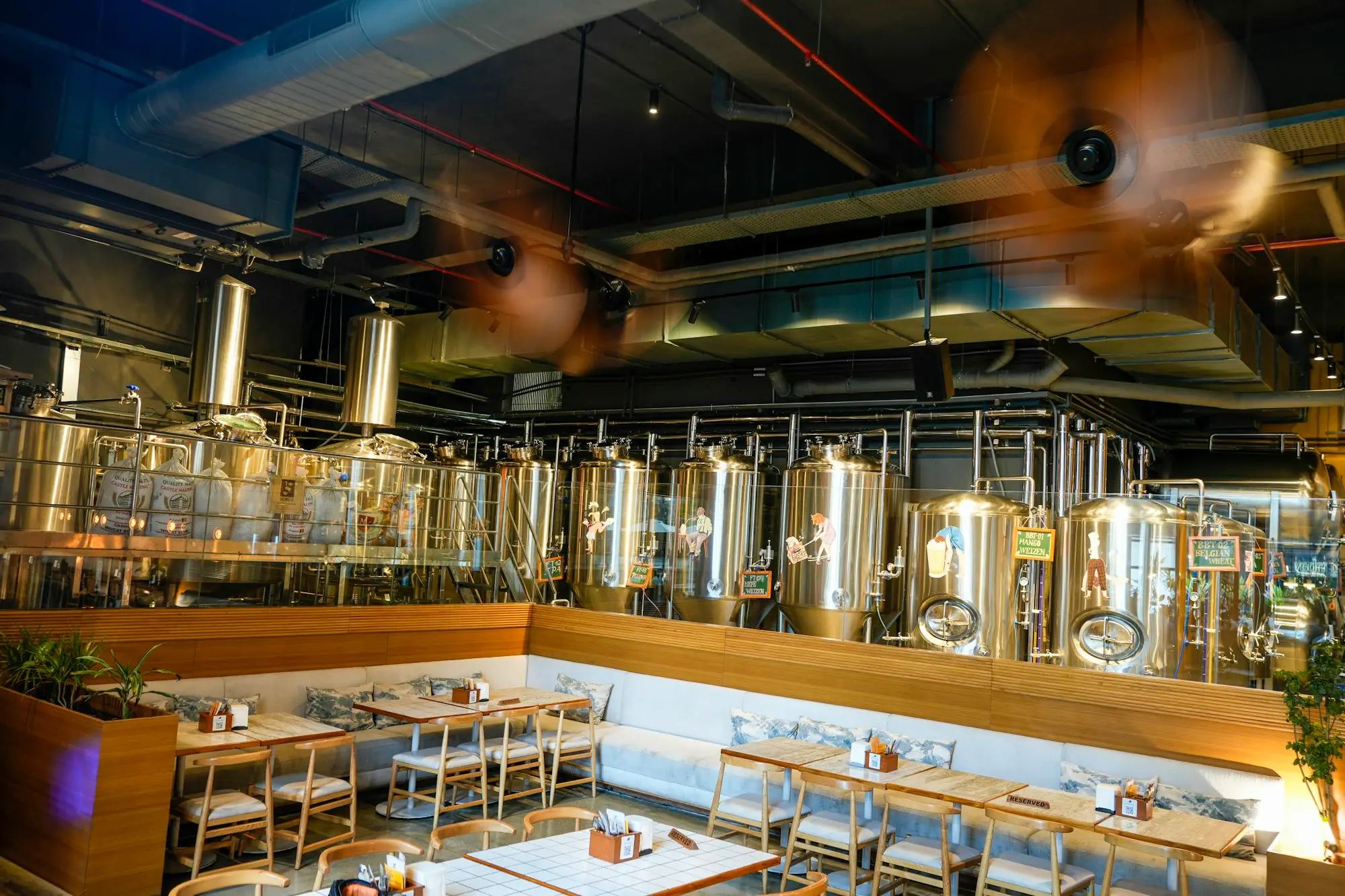 Brewery restaurant with stainless steel fermentation tanks behind the dining tables, the kind of fit-out a 200k business loan funds