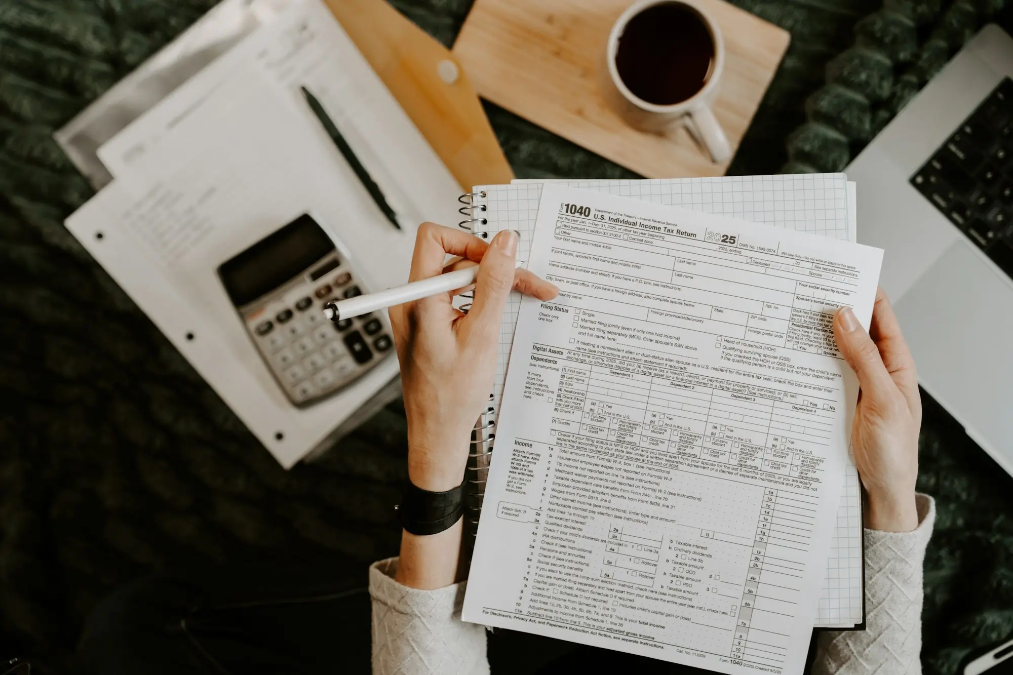 Hands holding a pen over printed loan paperwork beside a calculator