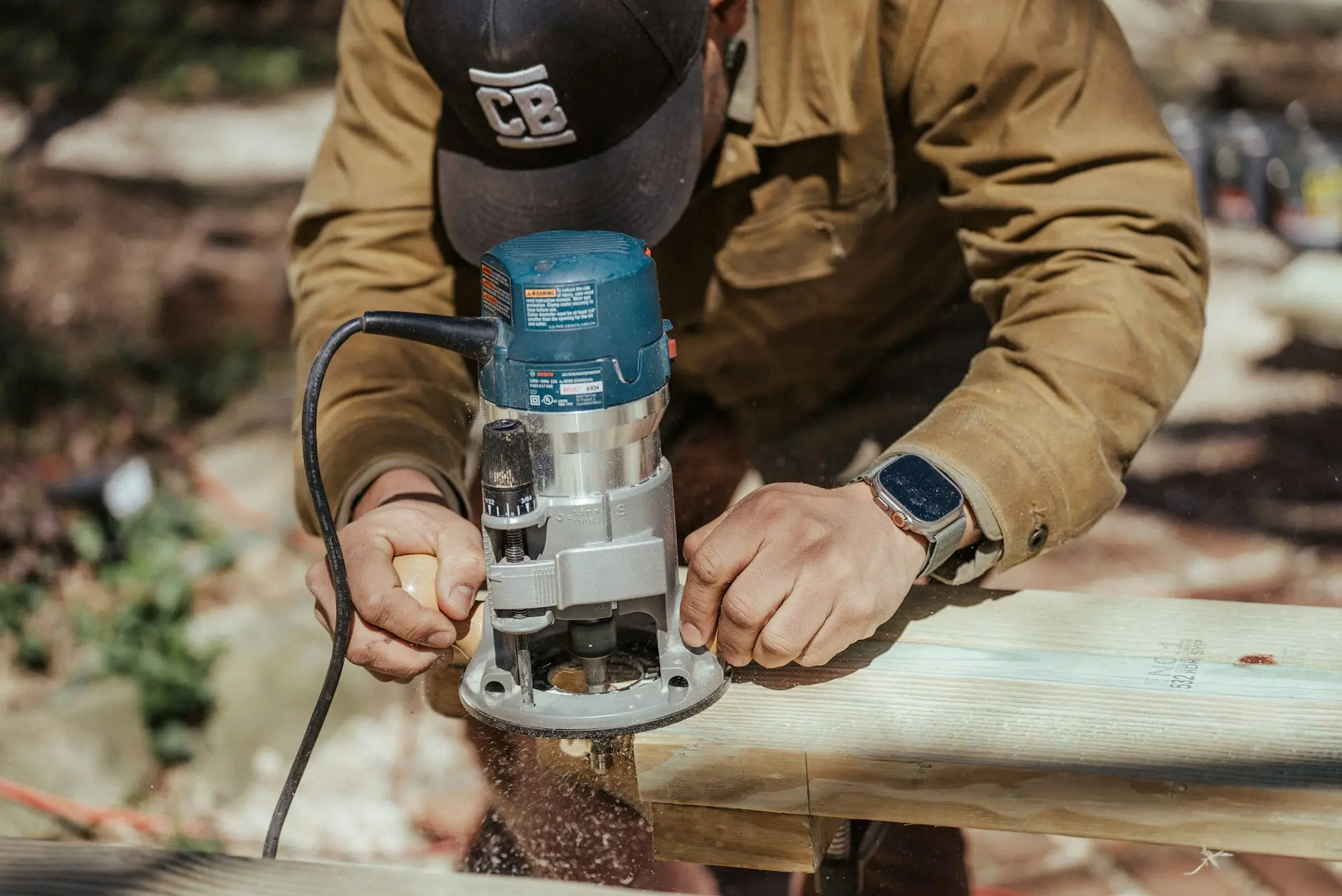 Tradie in work gear using a power router on a timber job